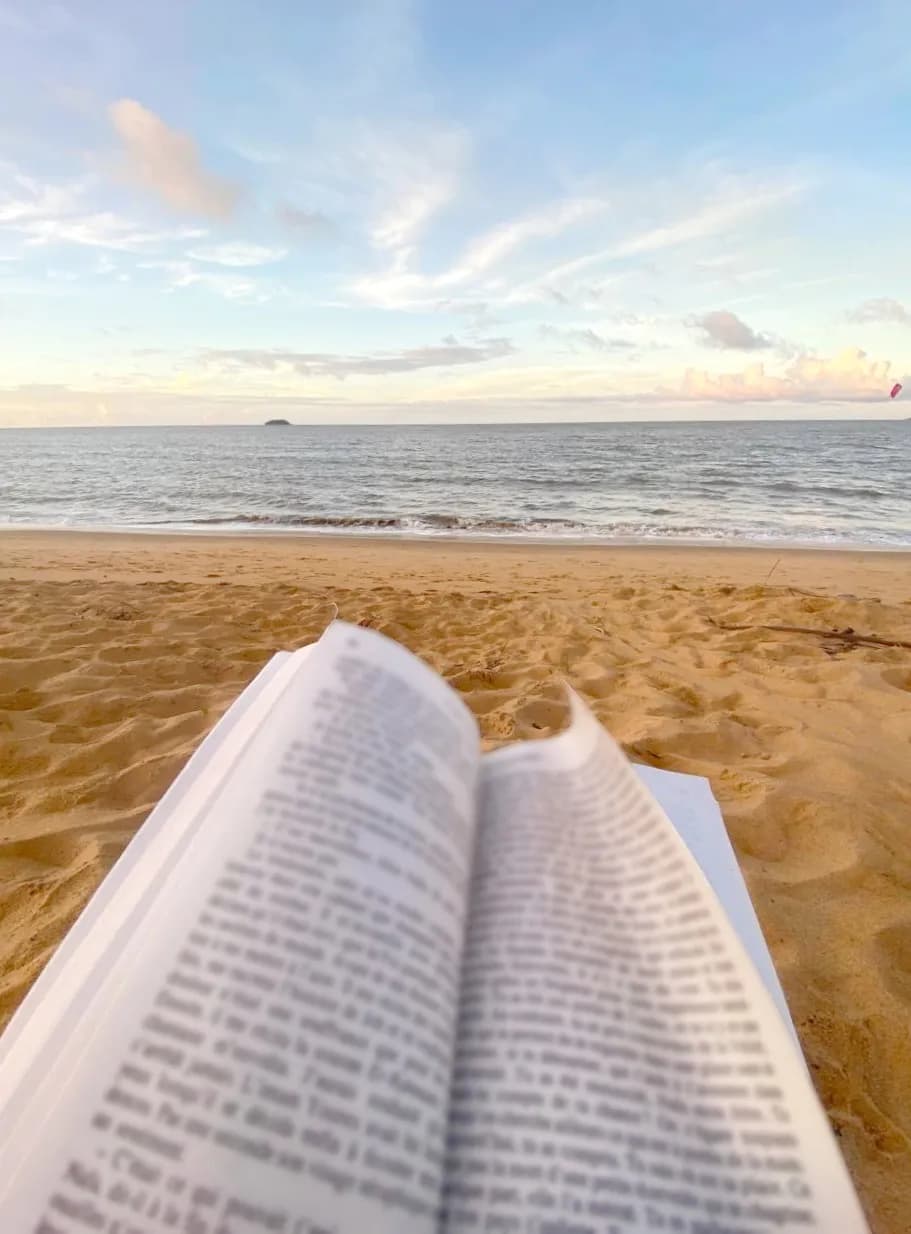 Un livre posé sur le sable face à la mer